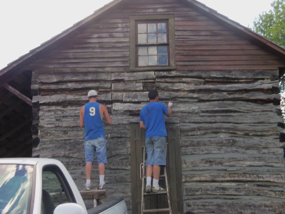 The Wilsons apply new chinking to the cabin walls.