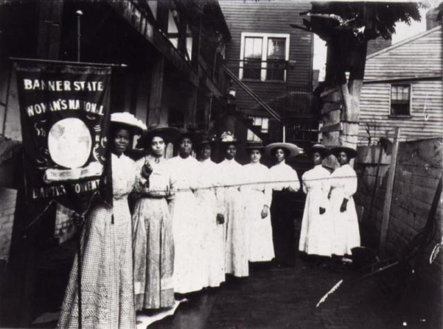 Several African American Women lobbying for the right to vote stand in a line.