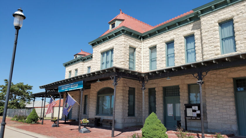 Exterior of a two-story limestone building with a red metal roof