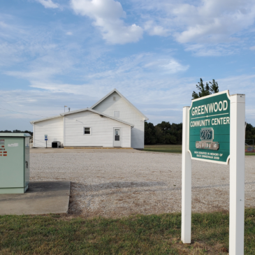 A one-room school building. Sign reads Greenwood Community Center.