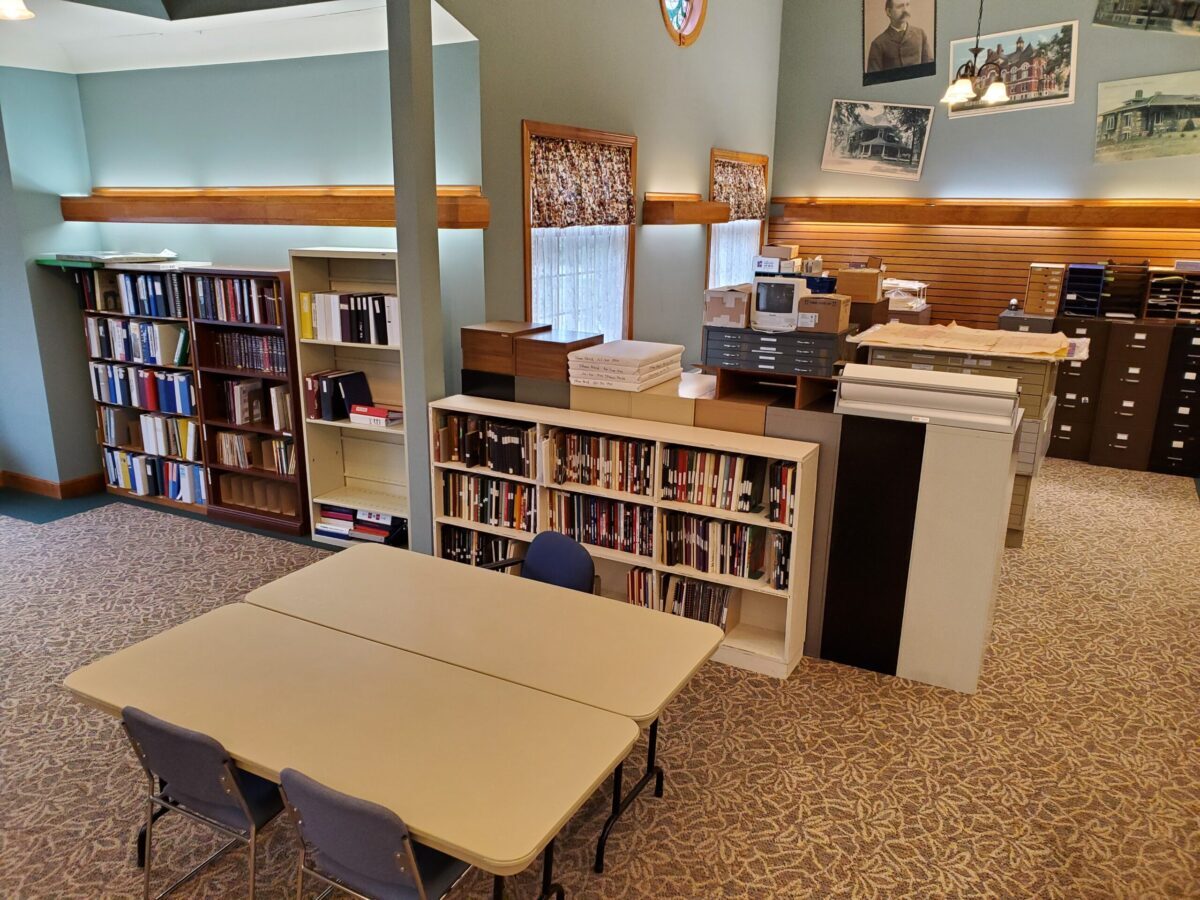 Bookcases filled with books. Tables and chairs. File cabinets. Large prints of historic photos in the background.