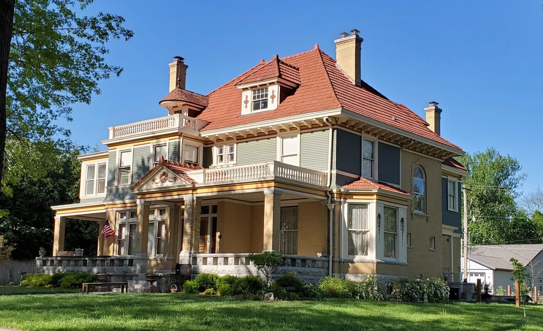 2 1/2 story Italian Renaissance Revival house with a red tile roof, brick first floor, and large wrap-around porch.